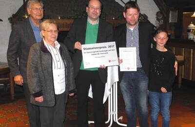 Minister Meyer (m) überreicht den Preis an Henning Müller (2.v.r.) in Gegenwart von Henning Müller sen. und Ehefrau Lisa sowie dem Sohn Pascal (r.)